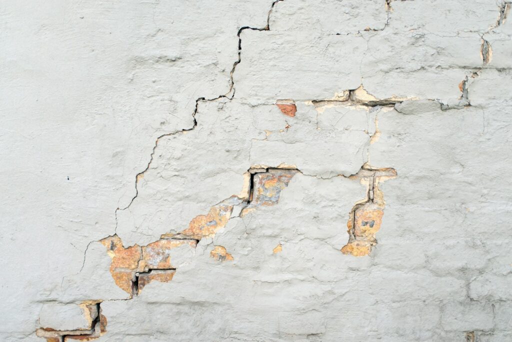 Fissure traversant le mur enduit d’une maison