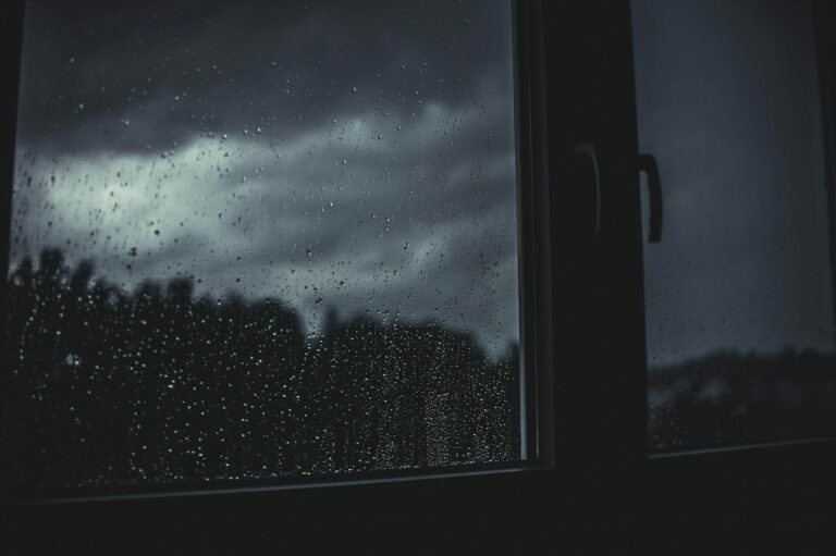 Pluie d’orage sur une vitre, ciel sombre à l’extérieur